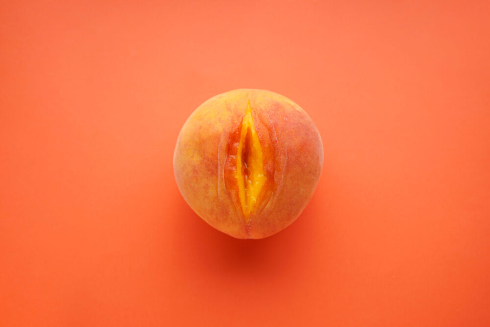Flat lay composition with ripe peach on a orange background. Sex concept