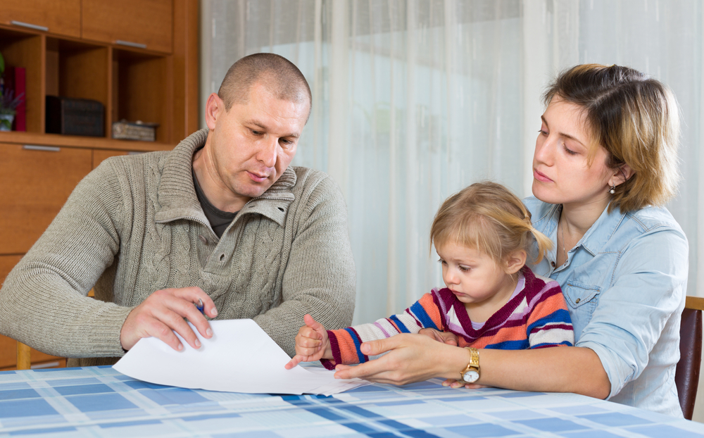 Upset couple with child sitting at the table with financial documents