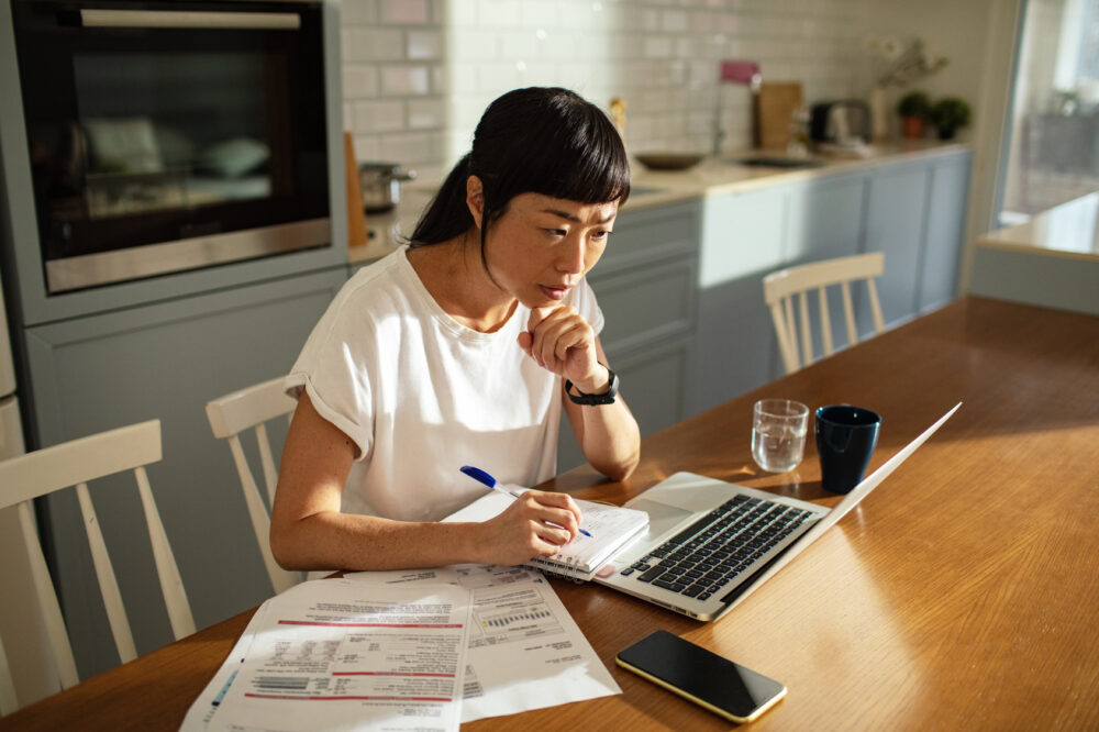 Young asian woman going over bills and home finances at home Young asian woman going over bills and home finances at home